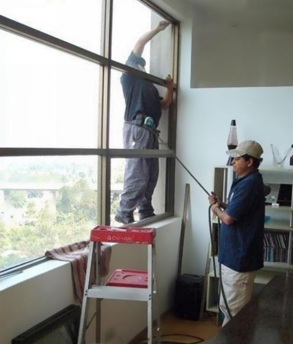 Hombre sujetando a otro con una cuerda mientras está afuera de una ventana 