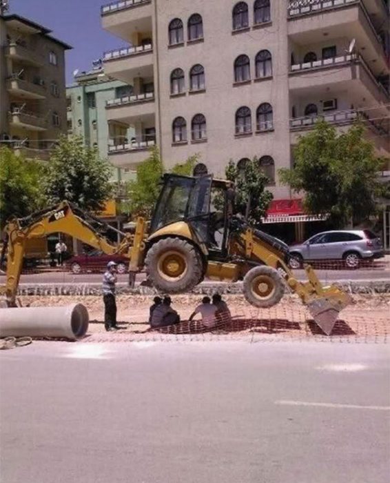 tractor colocado para que le de sombra a unos hombres 