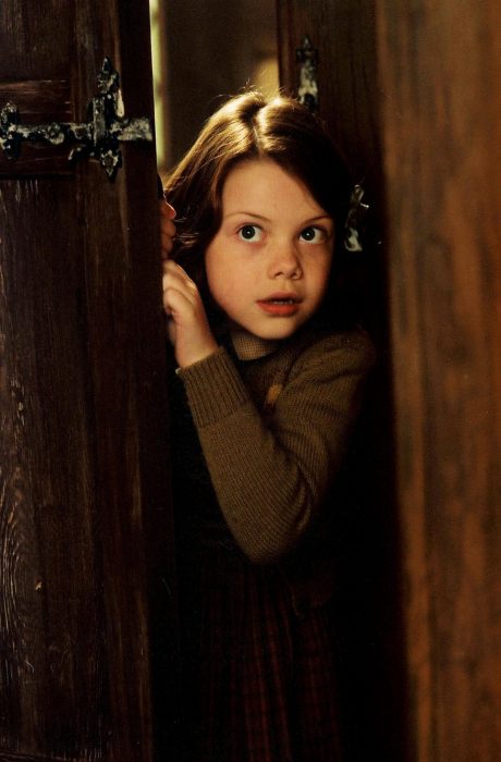 Escena de la película las crónicas de narnia lucy asomándose por una puerta