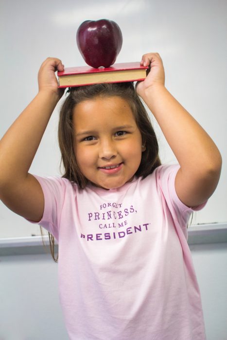 niña con libro en la cabeza y playera con mensaje