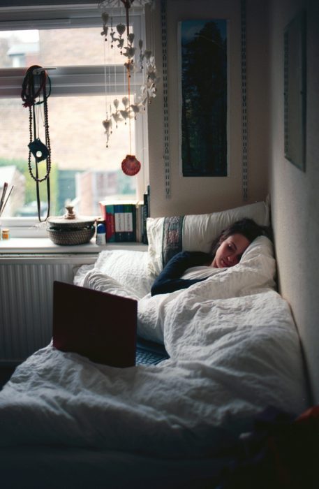 Chica recostada en una cama viendo su computadora 