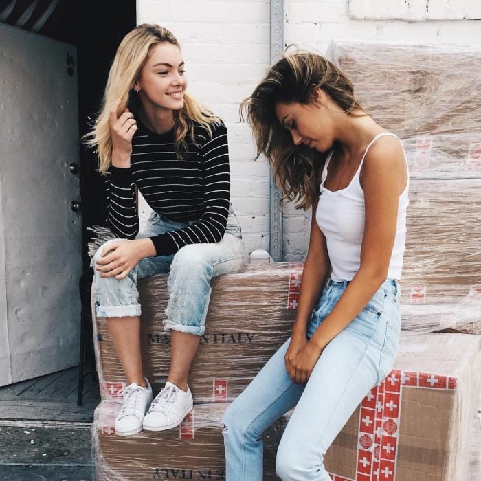 Chicas sentadas sobre unas cajas conversando 