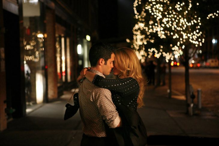 Pareja de novios abrazados y besándose en medio de la calle 