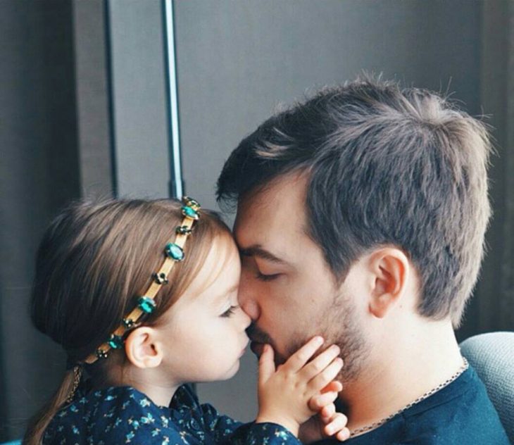 Padre besando en la frente a su hija 