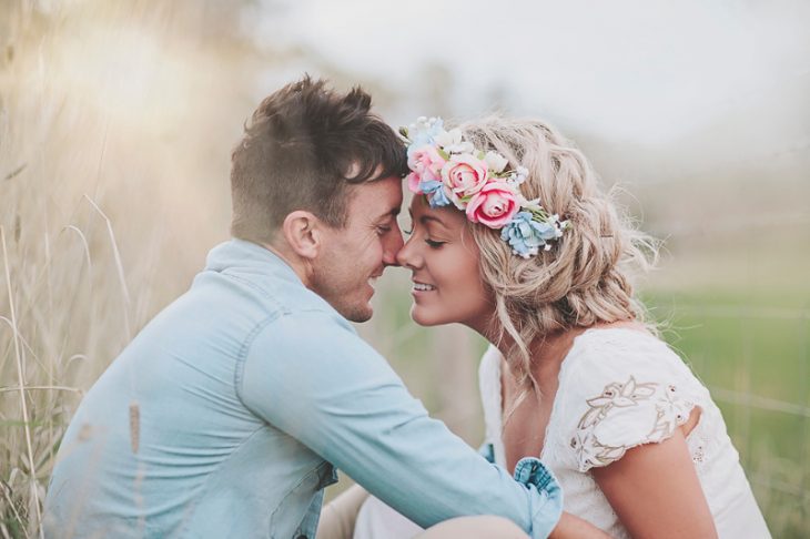 Pareja de novios sentados en el pasto besándose 