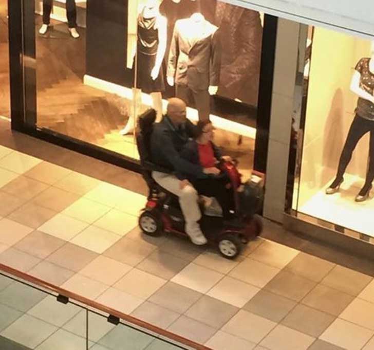 pareja de viejitos en una silla de ruedas motorizada 