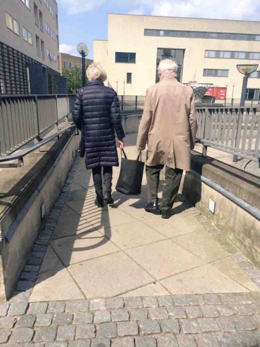 Pareja de ancianos cargando una bolsa entre los dos 