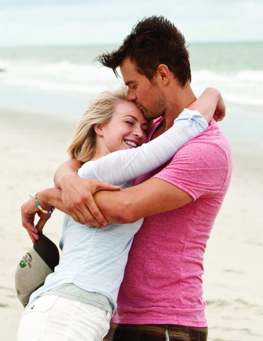 Pareja de novios abrazados mientras están parados junto al mar