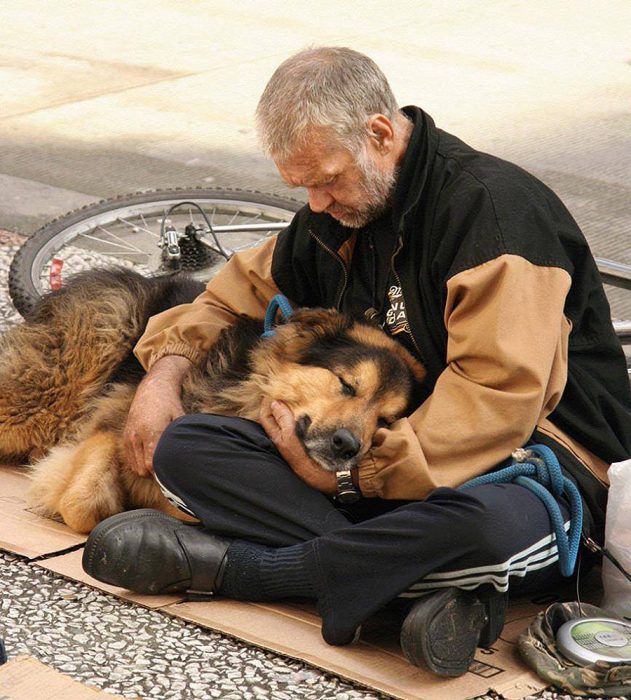 Anciano indigente abrazando a su perro 