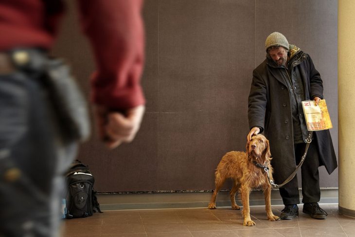 Persona sin hogar acariciando a su perro 