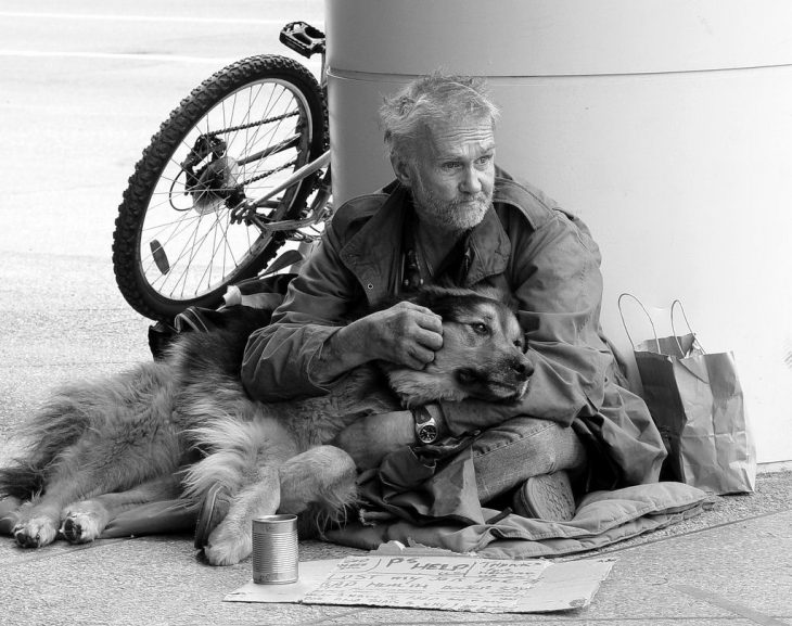 Hombre sin hogar abrazando a su perro 