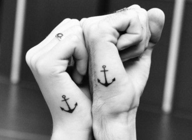 pareja mostrando sus puños donde tienen un tatuaje de anclas 