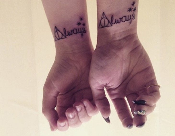 pareja mostrando sus manos con tatuajes de harry potter 