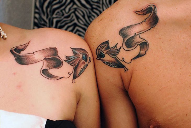 Pareja mostrando sus tatuajes de pájaros en el pecho 