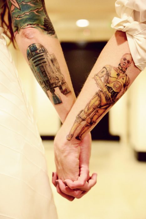 Pareja tomados de las manos mostrando sus tatuajes de star wars 