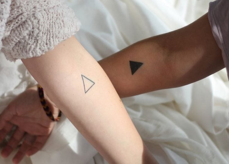 Pareja mostrando sus tatuajes de triángulos 
