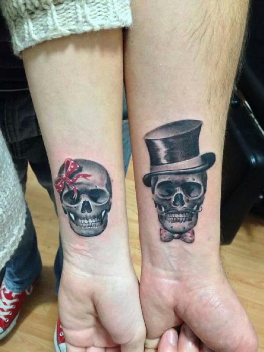 Pareja mostrando sus tatuajes en el antebrazo de calaveras