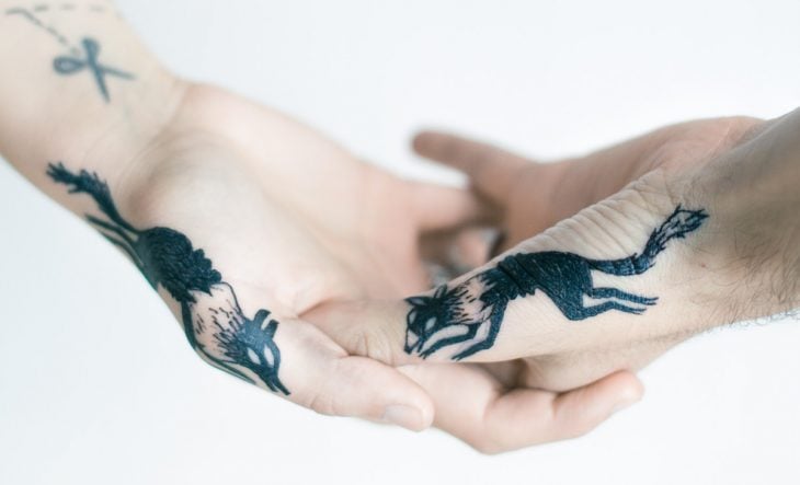Pareja mostrando sus tatuajes de zorros en las manos