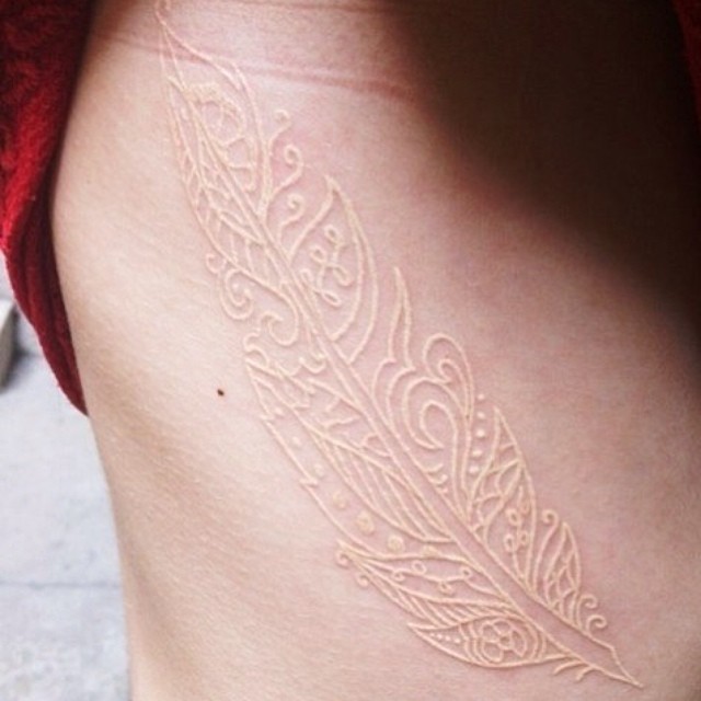 Tatuaje de pluma hecho con tinta blanca 