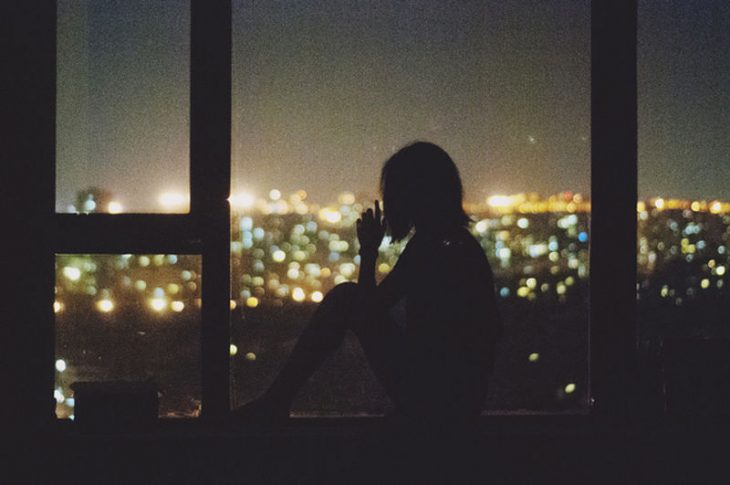 chica mirando fuera de la ventana de noche