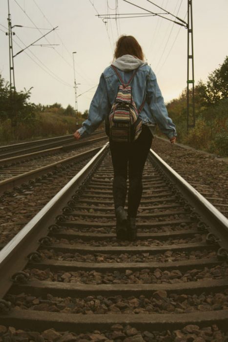 chica caminando por vías del tren