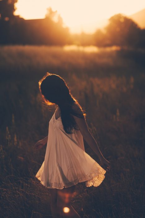 chica caminado en el campo al atardecer