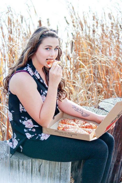 Chica sentada comiendo pizza