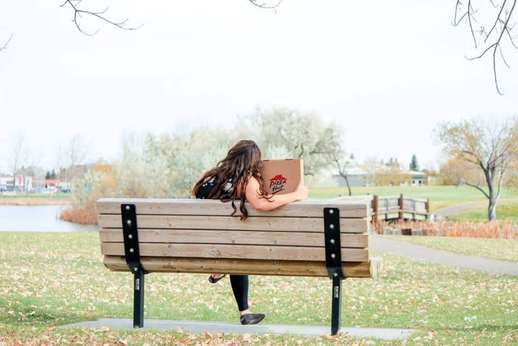 Chica sentada junto a una caja de pizza