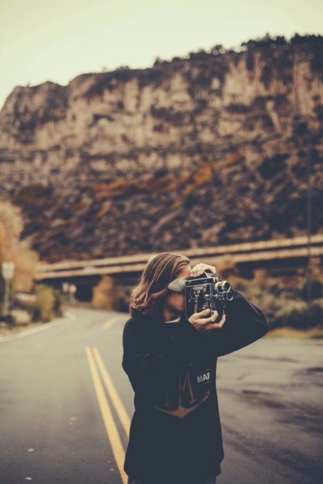 chica tomando fotos en carretera