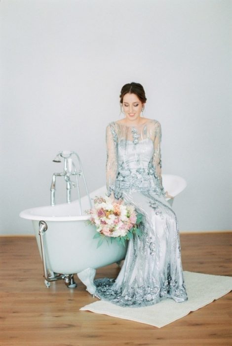 Chica con un vestido de novia de color verde sentada en una bañera 