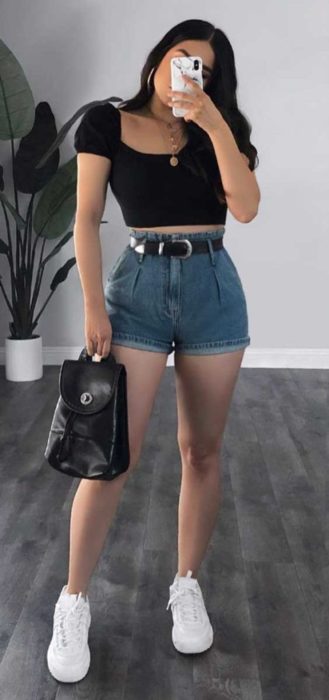 Chic asando shorts de cintura alta y un top de color negro con tenis 