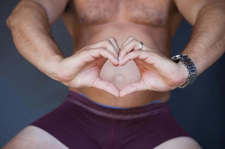 Hombre haciendo un corazón con las manos frente a su estomago 