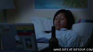GIF chica recostada en la cama viendo la computadora 