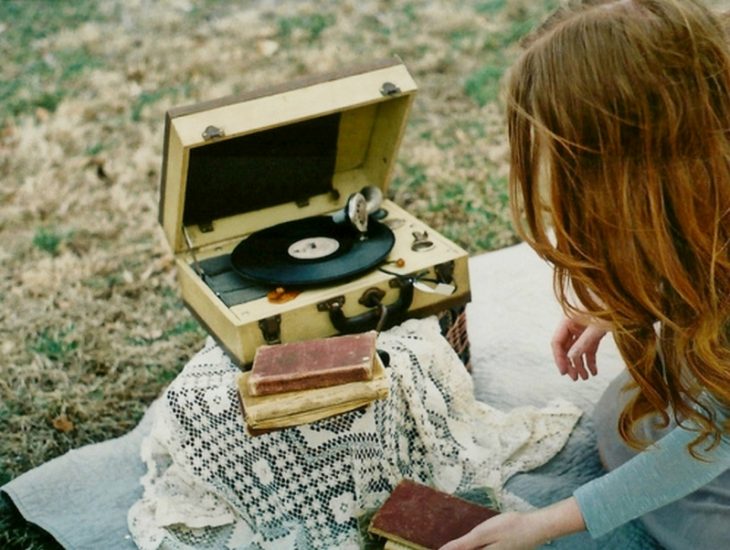 gif chica escuchando música y leyendo en campo