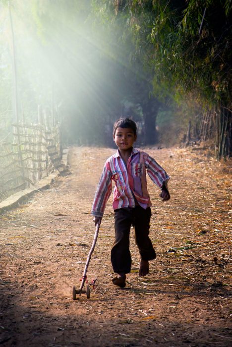 niño jugando con un palo con ruedas