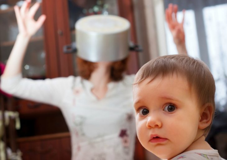 mamá con una olla en la cabeza y bebé volteando a la cámara