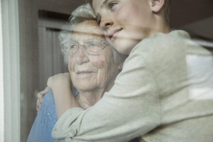 Abuela y nieta abrazadas en la ventana 