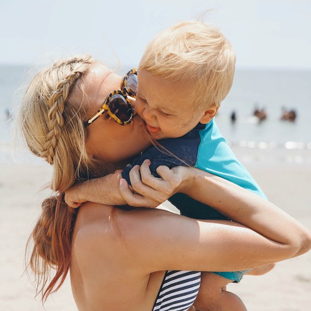 Chica abrazando a un bebé en la playa 