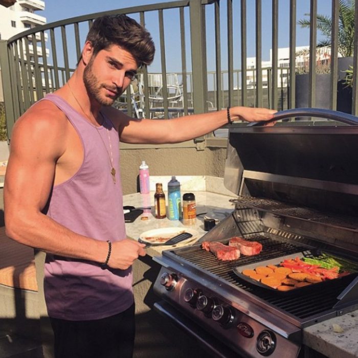 Hombre guapo cocinando carne asada 