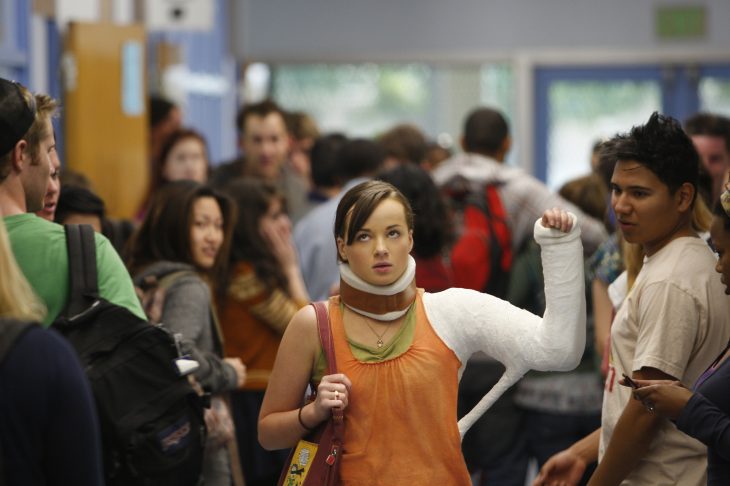 Escena de la serie that girl chica con el brazo quebrado caminando por los pasillos de una escuela