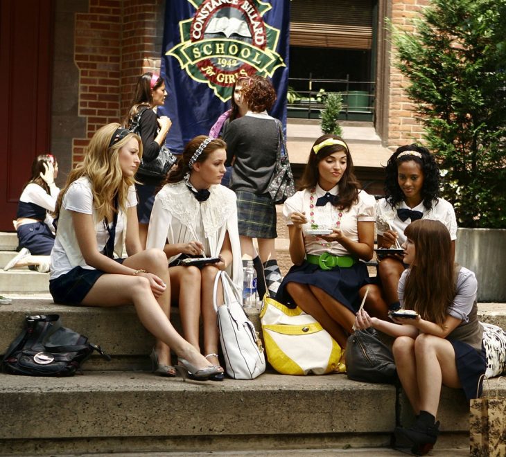 Escena de la serie gossip girls chicas sentadas fuera de la escuela conversando 