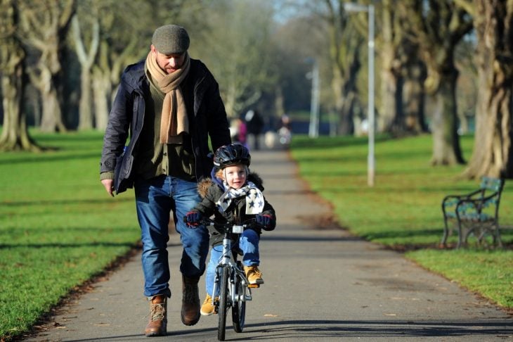 Papá cuida a su hijo que pasea en bicicleta