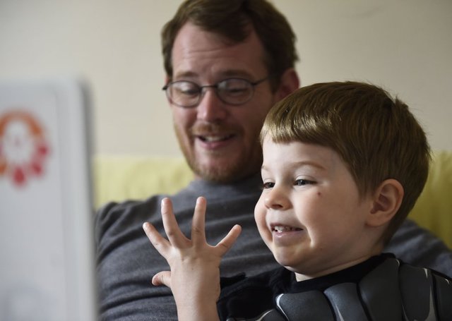 Papá en la computadora junto a su hijo