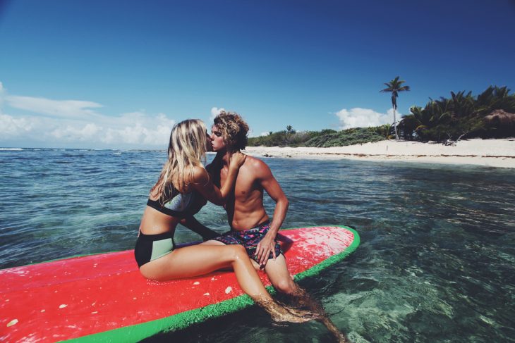 Pareja surfeando en la playa 