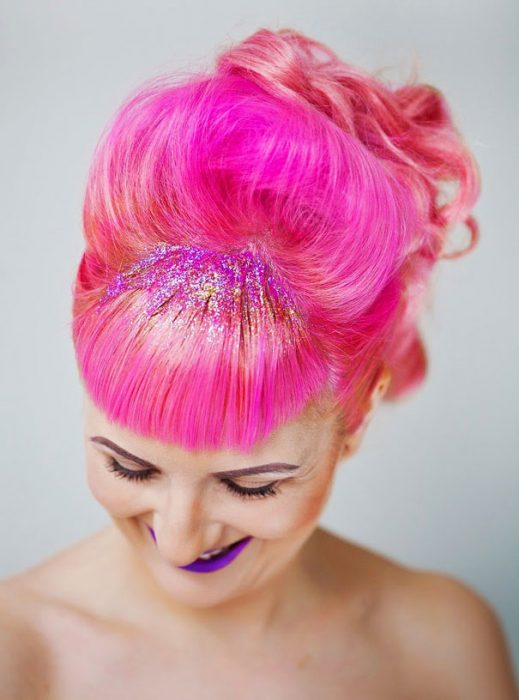 Chica con el cabello rosa y con brillos rosa y naranja en el copete 