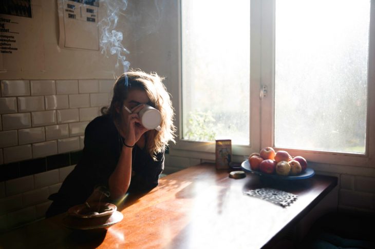 Chica tomando un café y fumando un cigarro 