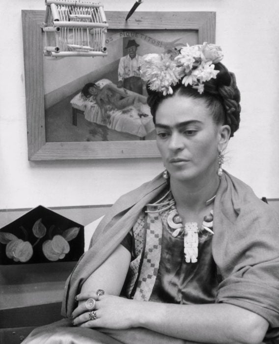 Frida Kahlo sentada frente a uno de sus cuadros en 1945