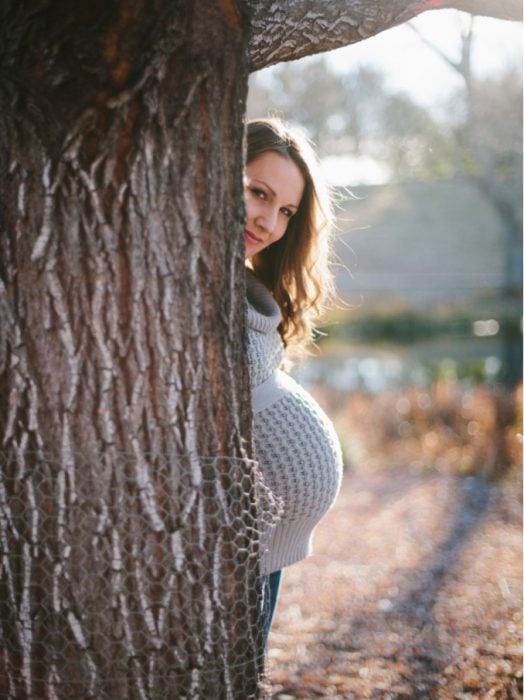 Sesión de fotos de maternidad chica oculta tras un árbol 