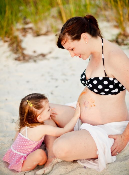 sesión de fotos de maternidad niña tocando el vientre de su mamá 