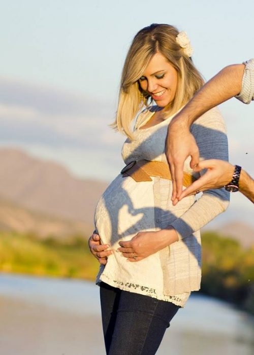 Sesión de fotos de maternidad hombre haciendo un corazón sobre el vientre de una mujer 